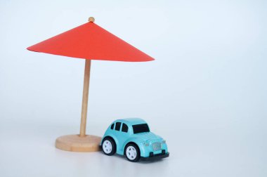 Red toy umbrella and blue toy car on white background. clipart