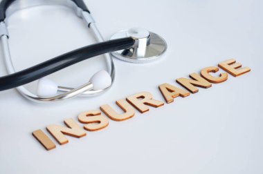 Beyaz arka planda sigorta metni olan bir doktor steteskobu. Hayat sigortası kavramı.