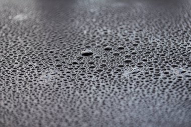 Koyu arkaplanda su damlacıklarının yan görünümü.