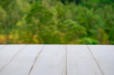 Ürünlerinizi göstermek veya montajlamak için özelleştirilebilir alanı olan bulanık doğa arkaplanının önündeki boş tahta tablo.