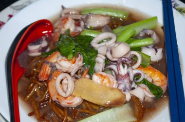 Deniz ürünleriyle servis edilen soslu eriştenin yakın görüntüsü. Asya gıda kavramı.