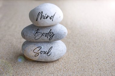 Zihin, beden ve ruh Zen taşları üzerinde parlak ışıkla yazılmış. Meditasyon kavramı.