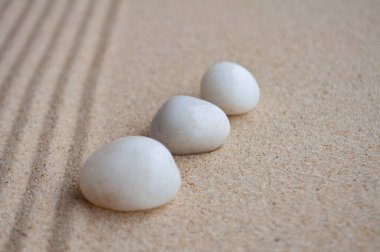 Beyaz zen taşları, metin için özelleştirilebilir alanla kumun üzerinde dizilirler.