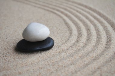 Metin için özelleştirilebilir alanı olan kumda beyaz ve siyah zen taşları.