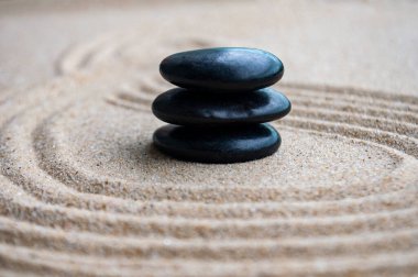 Metin için özelleştirilebilir alanı olan kumda siyah zen taşları.