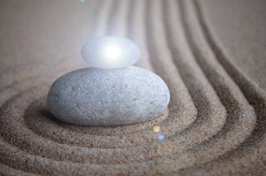 Metin veya mesaj için özelleştirilebilir alanı olan kumun üzerinde parlayan ışık ile Zen taşları.
