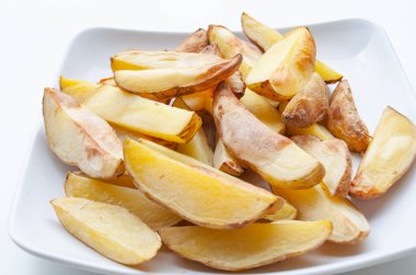 Bir parça fırın kağıdının üzerinde taze patates parçaları yakın çekim. Sağlıklı gıda konsepti