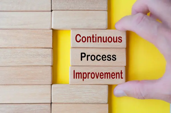 stock image Hand pulling wooden blocks with continuous process improvement text. Business culture and Operational excellence concept.