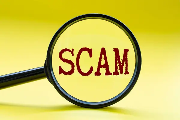 Sarı kapaklı SCAM metnine odaklanan büyüteç. Siber güvenlik kavramı.