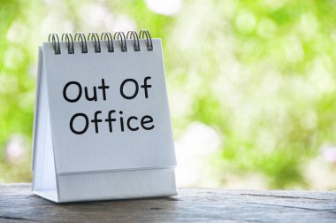 Ofis dışı mesajı beyaz not defterinde, parlak yeşil bir arka planı var. Tatil ya da tatil kavramı.
