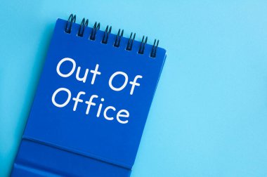 Ofis dışı metnin mavi not defterindeki üst görünümü. Yıllık izin konsepti.