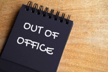 Ofis dışı metnin en üst görüntüsü siyah not defterinde. Yıllık izin konsepti.