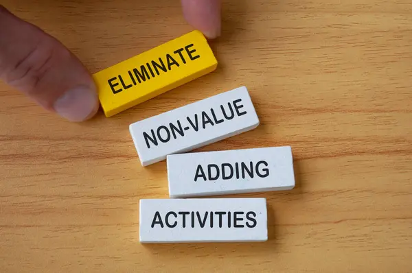 Stock image Top view of hand holding wooden blocks with text Eliminate non-value added activities. Process improvement concept.