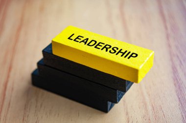 Liderlik metni, siyah tahta bloklara istiflenmiş sarı tahta blokta. Liderlik kavramı.