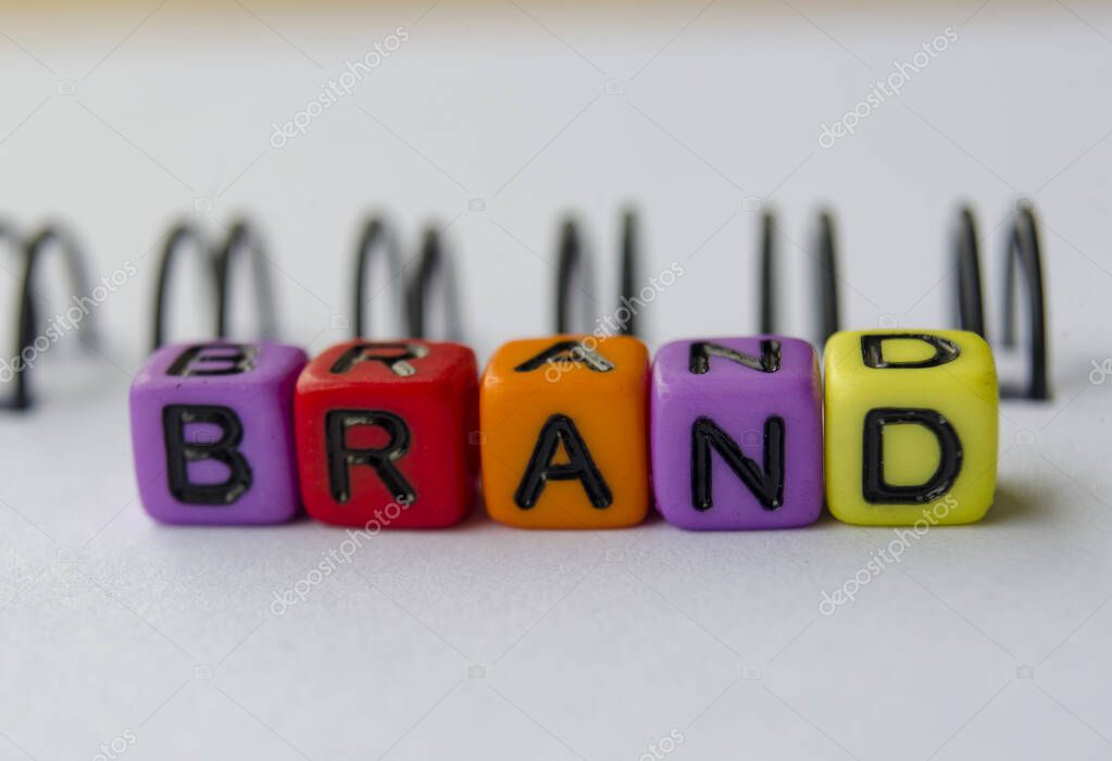 Close up of BRAND text representing on small square toy on white background.