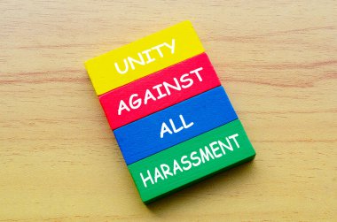 Top view of Unity Against All Harassment text on multicolored wooden blocks. Against discrimination and harassment concept. clipart