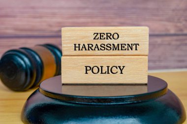 Sıfır Taciz Politikası metni tahta bloklara yazılmış, tokmak arkaplanlı. Güvenli işyeri kavramı.