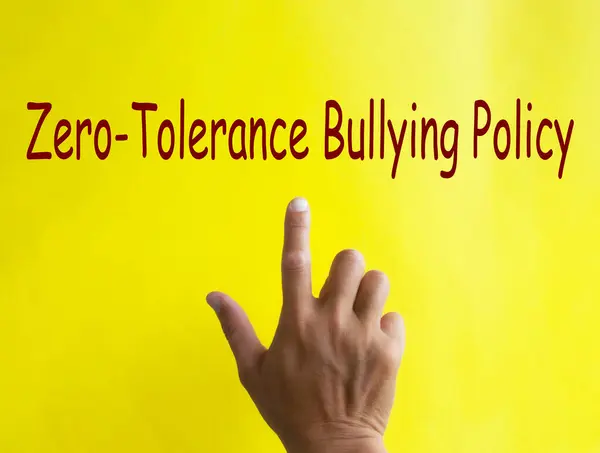 stock image Hand pointing at Zero Tolerance Bullying Policy text written on yellow cover. Safe workplace concept.