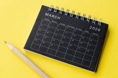 Mart 2026 tarihli takvimin en üst görüntüsü sarı arka planlı siyah not defterinde. Takvim kavramı.