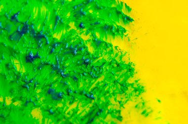 Sarı arkaplanda yeşil suluboya fırça darbelerinin üst görünümü.