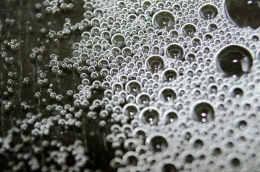 Su yüzeyinde koyu arkaplan oluşturan baloncukların makro görünümü.