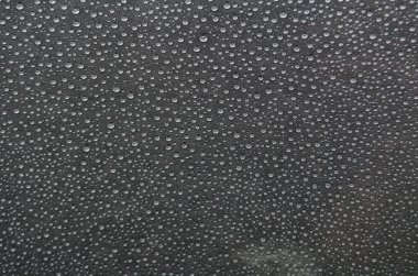 Koyu örtülü arka planda küçük yağmur damlacıkları.