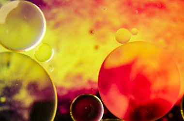 Su yüzeyinde benzersiz şekiller oluşturan petrol baloncuklarının yakın çekimi, hafif bir gradyan üzerine kurulu, dinamik bir duvar kağıdı için ideal.