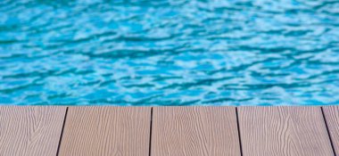 Yüzme havuzunun ahşap zemininde yazı ve fikirler için özelleştirilebilir alan var. Boşluk ve tatil konseptini kopyala.