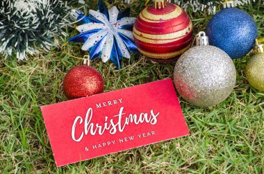 Top view of Merry Christmas wishes text on red card with Christmas balls decoration background. Christmas celebration concept. clipart