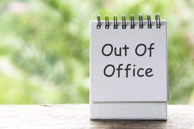 Bulanık doğa arka planına sahip beyaz not defteri üzerinde ofis dışı metin.