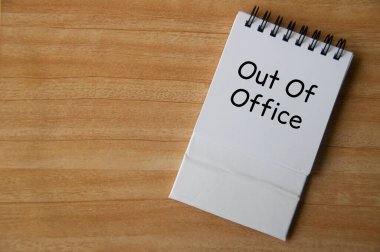Ofis dışı metnin en üst görüntüsü ahşap masadaki beyaz not defterinde. İş konseptinden uzakta.