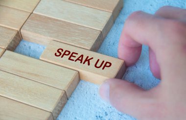 Hand pulling wooden block with text SPEAK UP. Courage concept. clipart