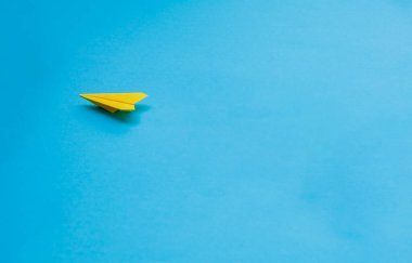 Mavi arkaplanda sarı kağıt uçak.