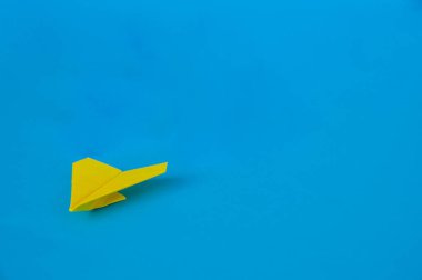 Mavi arkaplandaki sarı kağıt uçağın yan görüntüsü ve metin için özelleştirilebilir boşluk. İş ve Liderlik becerileri kavramı.