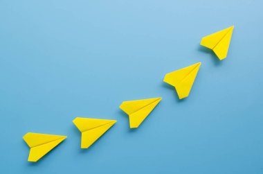 Origami sarı kağıttan uçağın en üst görüntüsü başarılı olma vizyonuyla uçuşu yönetiyor. Liderlik kavramı.