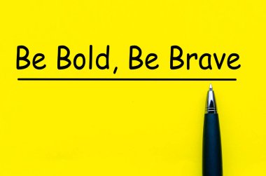 Be Bold and Be Brave text on yellow notepad with pen background. clipart