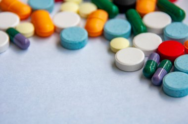 Açık renkli bir yüzeye yayılmış renkli hap ve kapsüllerin yan görünümü ve metin için özelleştirilebilir alan
