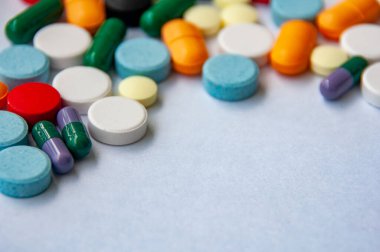 Açık renkli bir yüzeye dağılmış renkli hapların ve kapsüllerin üst görünümü metin için özelleştirilebilir alan