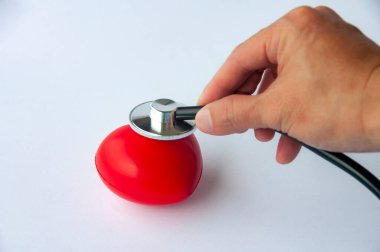 Stetoskop ile el ele tutuşmanın en üst görüntüsü ve yazılar için özelleştirilebilir alanı olan kırmızı bir kalp. Tıbbi ve sağlık konsepti.