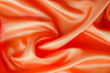Açık kırmızı renkli parlak saten kumaş, akışkan hareket ve parlaklığı gösteriyor. Tasarım ve duvar kağıdı arkaplanı için uygun.