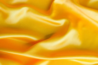 Pürüzsüz yüzeyi ve kıvrımları olan parlak sarı saten maddeyi kapat. Tasarım ve duvar kağıdı arkaplanı için uygun.