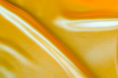 Yumuşak kıvrımlı ve canlı yansıtıcı yüzeyi olan altın sarısı ipeğin üst görüntüsü. Tasarım ve duvar kağıdı arkaplanı için uygun.