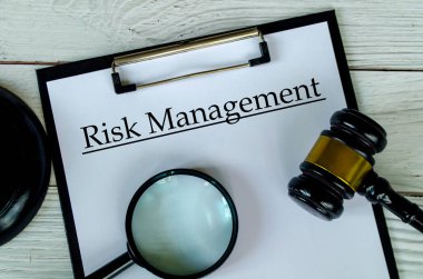 Tokmak ve büyüteçle beyaz kağıt pano üzerinde Risk Yönetimi metninin üst görünümü.