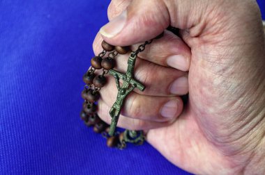 Boncuklu tespihi tutan bir el, sınamalar sırasında duaya ve cennet gücüne duyulan güveni ortaya çıkarır.