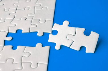 Kayıp beyaz yapbozların, ortaklığın ve mavi arkaplanda birliğin sembolü olan yapbozların yakın görünümü.
