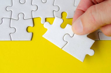 Yazı veya fikirler için yapboz üzerinde özelleştirilebilir alanı olan parlak sarı arkaplan üzerindeki yapboz parçalarını tutan el görünümü.