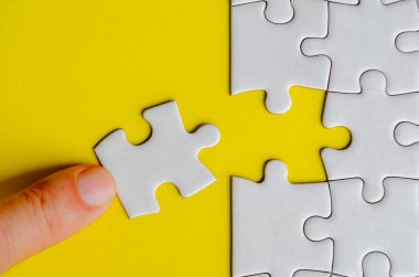 Beyaz bir yapbozu orijinal konumuna bağlayan elin üst görüntüsü. Çözüm kavramı.