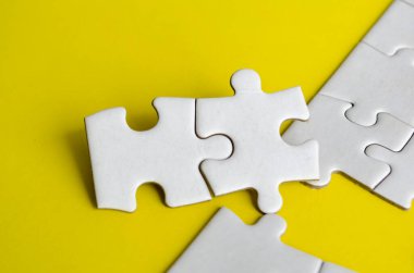 Birbirine kenetlenmiş yapboz parçalarının yakın görüntüsü takım çalışmasını ve işbirliğini sembolize ediyor. Çözüm kavramı.