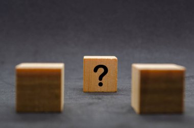 Siyah arka planda soru işaretleri olan iki siyah tahta küp..