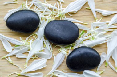 Bambu hasırının üzerinde duran pürüzsüz taşlar. Sarı yapraklar nazikçe dağılmış. Kişiselleştirilebilir alanla birlikte..